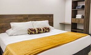 A neatly made bed with white linens and a mustard-colored throw blanket. - Hotel Boutique Estadio Medellin (Medellín)