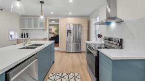 Une cuisine moderne dotée d’un îlot central, d’appareils électroménagers en acier inoxydable et de meubles de couleur bleu clair.