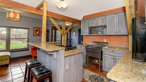 A kitchen with granite countertops, wooden beams, and a large island. - Luxury Barn with Best View in the Cuyahoga National Park.   (Peninsula)