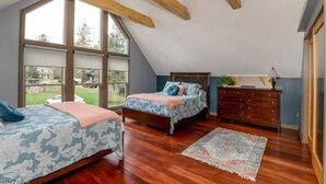 A bedroom with two beds, wooden beams, large windows, a dresser, and a rug. - Luxury Barn with Best View in the Cuyahoga National Park.   (Peninsula)