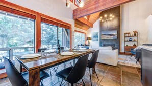 A modern dining area with a wooden table set for four, surrounded by black chairs.