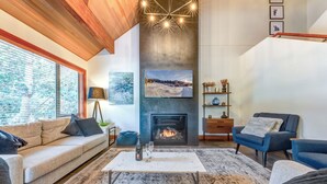 A cozy living room with a fireplace, a sofa, a coffee table, and a bookshelf.