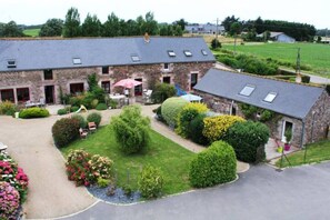 A large stone building with multiple windows and a covered outdoor seating area. - Les Gites du Buisson (Fréhel)