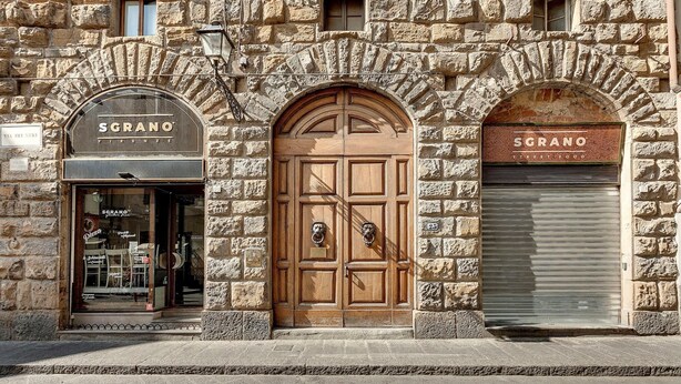 A stone building with three storefronts, one of which is closed. - Neri 23 in Firenze With 3 Bedrooms and 2 Bathrooms (Florence)