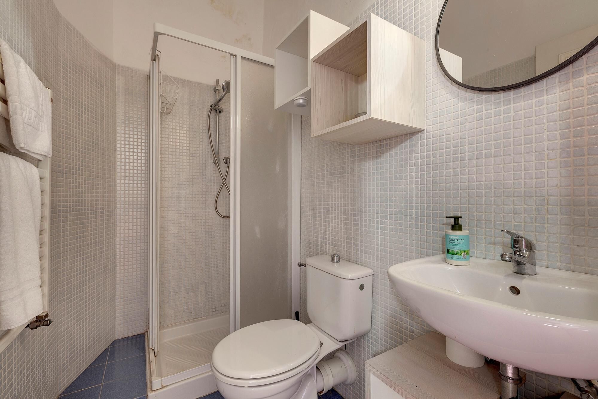 Un baño con ducha de mampara de vidrio, inodoro, lavamanos y espejo.
