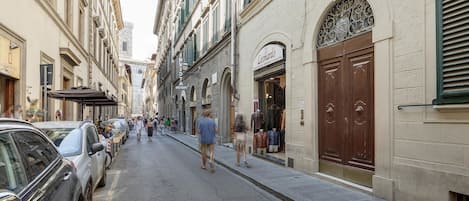Una calle estrecha flanqueada por edificios históricos, algunos con tiendas y cafés.