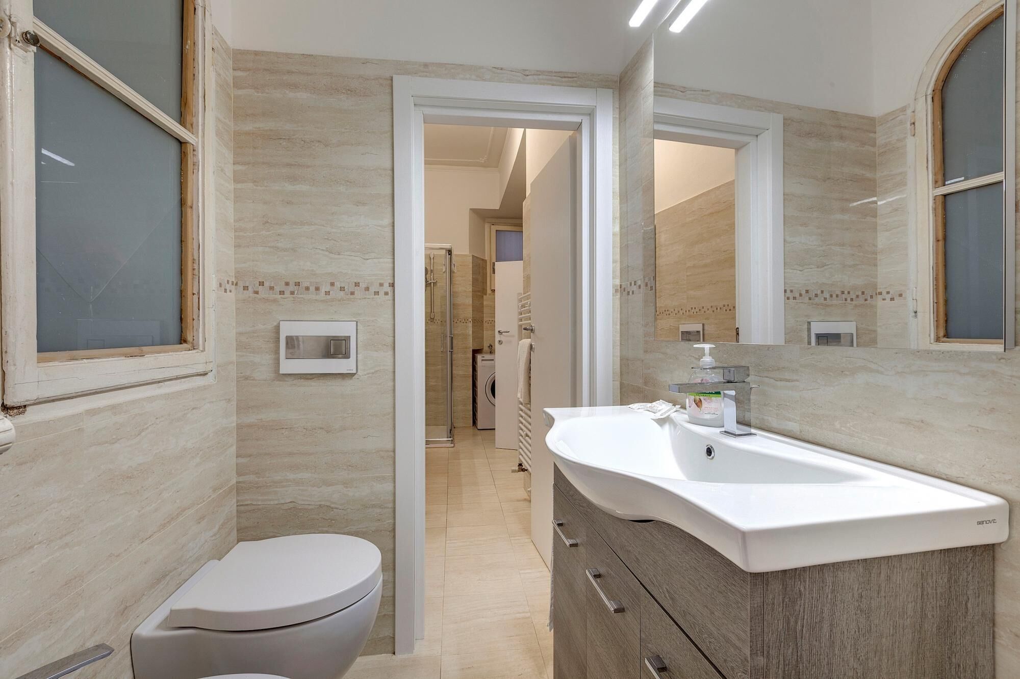 A bathroom with a white toilet, a sink with a mirror, and a shower area.
