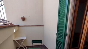A small outdoor patio with a round table and two chairs, a hanging basket, and a door with green shutters. - Agnolo 73 IV in Firenze (Florence)