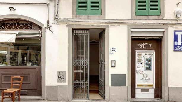 A building with a shop entrance, a door with a number plate, and a vending machine. - Agnolo 73 IV in Firenze (Florence)