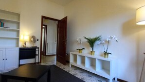 A room with a white cabinet, a black table, a white console table with potted plants, a standing lamp, and a door leading to another room. - Agnolo 73 IV in Firenze (Florence)
