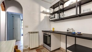 A compact kitchen with a built-in oven, a microwave, and a black countertop. There is a window above the microwave, and a door leading to another room. - Sapiti 2 G in Firenze (Florence)