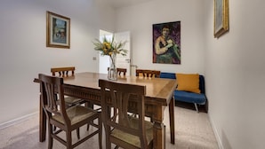 A dining area with a wooden table, chairs, a vase with flowers, and two paintings on the walls. - Greci 16 III in Firenze (Florence)