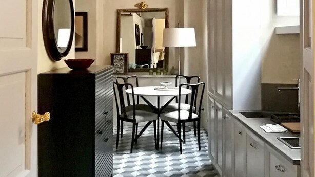 A narrow hallway with a checkered floor, a dining table with chairs, a mirror, and a lamp. - Mezzo 46 in Firenze With 2 Bedrooms and 2 Bathrooms (Florence)