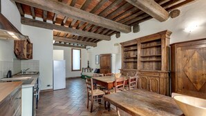 Une cuisine rustique avec des poutres apparentes, une grande table en bois et une bibliothèque intégrée.