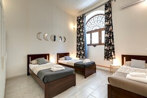 A bedroom with two single beds, a large window with floral curtains, and wall-mounted mirrors. - Santa Maria 3B in Firenze (Florence)