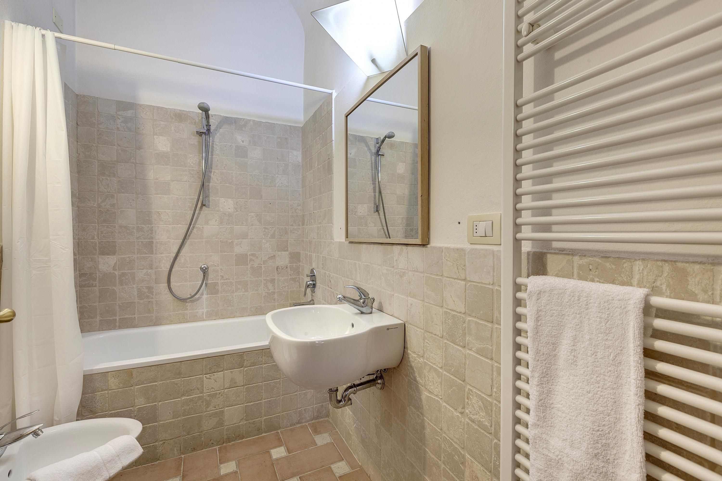 A bathroom with a bathtub, a sink, and a mirror.