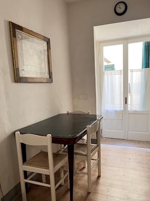 A dining area with a table and chairs, a framed picture on the wall, and a door leading outside.