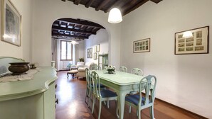 A dining area with a green table and chairs, a wooden ceiling, and framed pictures on the walls. - Pepi 51 in Firenze With 2 Bedrooms and 2 Bathrooms (Florence)