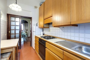 Una cocina con armarios de madera, estufa a gas, lavavajillas y salpicadero de azulejos.