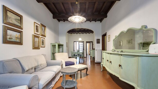 A living room with a sofa, armchair, and a small table. There are framed pictures on the wall and a cabinet with a mirror. - Pepi 51 in Firenze With 2 Bedrooms and 2 Bathrooms (Florence)