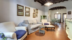 A living room with a sofa, armchairs, a small table, and a dining area with a table and chairs. - Pepi 51 in Firenze With 2 Bedrooms and 2 Bathrooms (Florence)