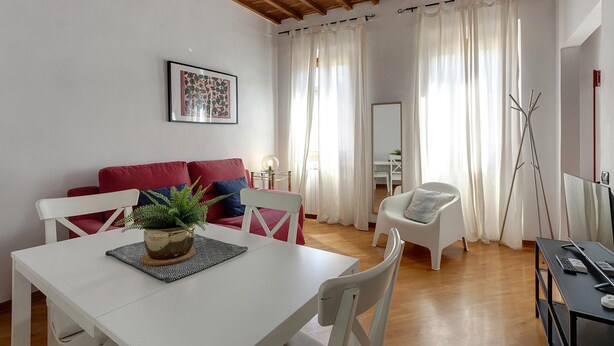 A modern living room with a white table, red and blue cushions, a potted plant, and a ceiling fan. - Santa Maria 10 in Firenze (Florence)