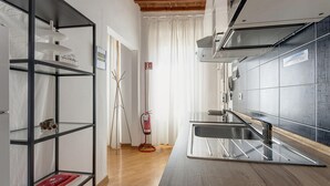 A modern kitchen with a stainless steel sink, a wooden ceiling, and a fire extinguisher near the entrance. - Santa Maria 10 in Firenze (Florence)