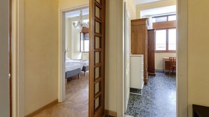 A hallway leading to a bedroom with a bed and a desk. - Ponte Vecchio 4 Bedrooms (Florence)