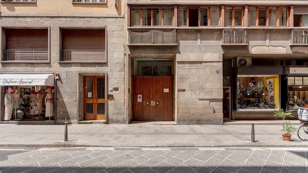 A street view of a building with a closed shop on the ground floor, a wooden door, and a balcony with railings. - Ponte Vecchio 4 Bedrooms (Florence)