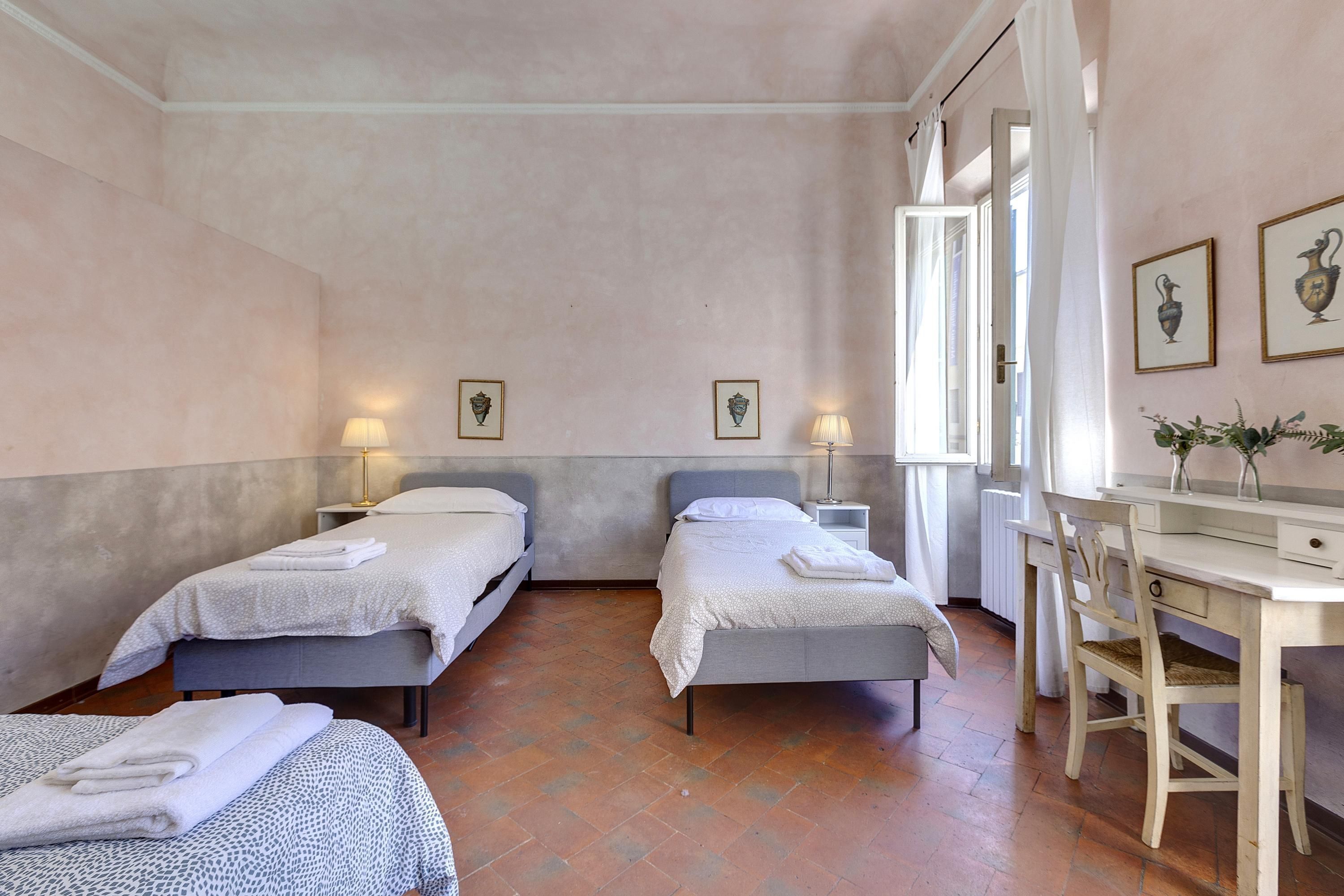 A bedroom with two beds, a desk, and a chair.