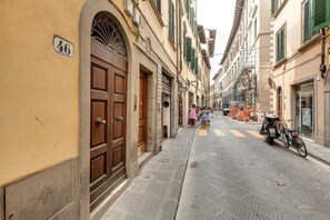 A narrow street with buildings on both sides, a few people walking, and a motorcycle parked on the right. - Pinti 46 in Firenze With 1 Bedrooms and 1 Bathrooms (Florence)