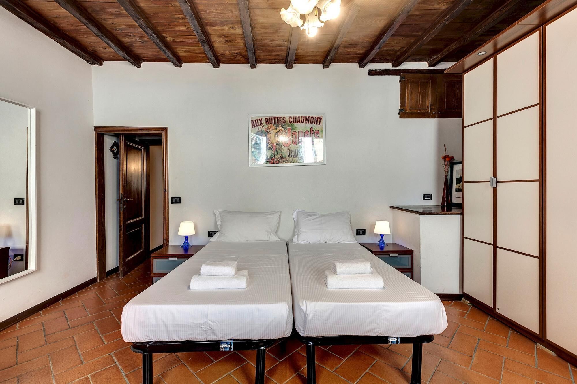 Une chambre avec un lit double, deux tables de chevet, un plafond en bois, une affiche au mur et une porte coulissante.