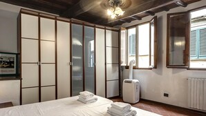 Ein Schlafzimmer mit Bett, Kleiderschrank, Heizkörper und einem Fenster mit Rollläden.