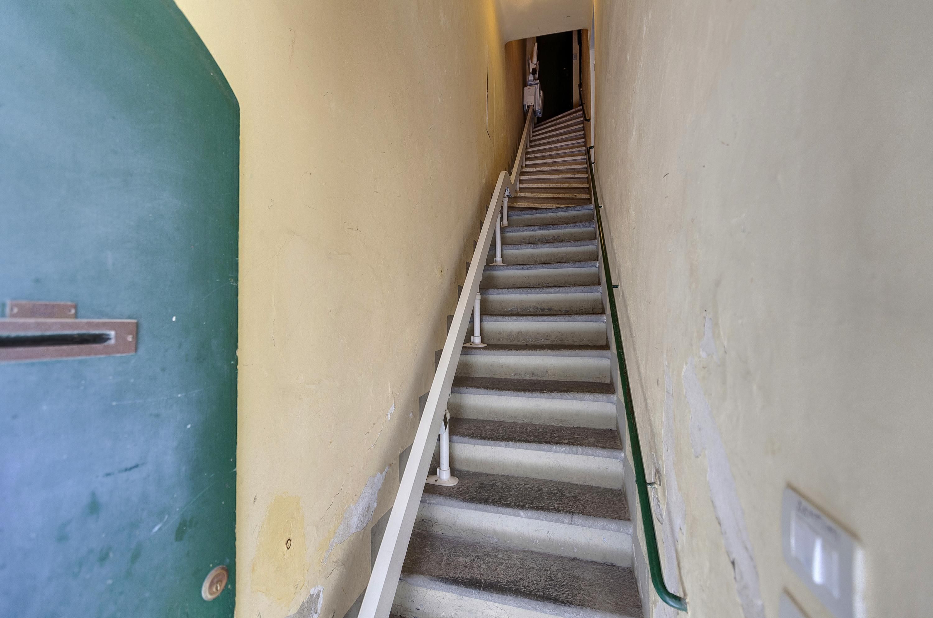 A staircase with a handrail, leading to a door at the top.