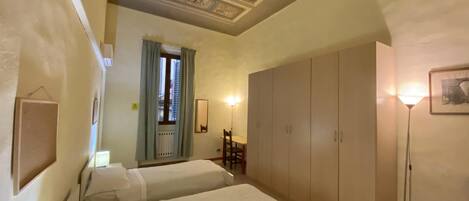 A bedroom with two beds, a wardrobe, a desk, and a chair.