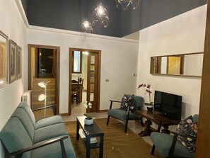 Una sala moderna con sofá, sillones, una mesa de centro, televisor y un comedor con mesa y sillas.