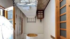 A narrow hallway with a white textured hanging lamp, a wooden cabinet with drawers, and a window with wooden frames. - Faenza 65 in Firenze (Florence)