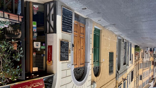 A building with a balcony, a signboard with text, and a window with a green shutter. - Faenza 65 in Firenze (Florence)