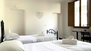 A hotel room with two single beds, a desk with a chair, a window with wooden shutters, and a geometric wall decoration. - Faenza 65 in Firenze (Florence)