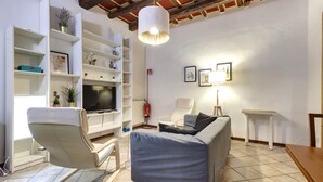A living room with a sofa, a television, a bookshelf, and a pendant light. - Faenza 65 in Firenze (Florence)