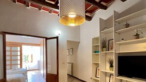 A spacious living area with a high ceiling, a patterned rug, and a TV stand with shelves. - Faenza 65 in Firenze (Florence)