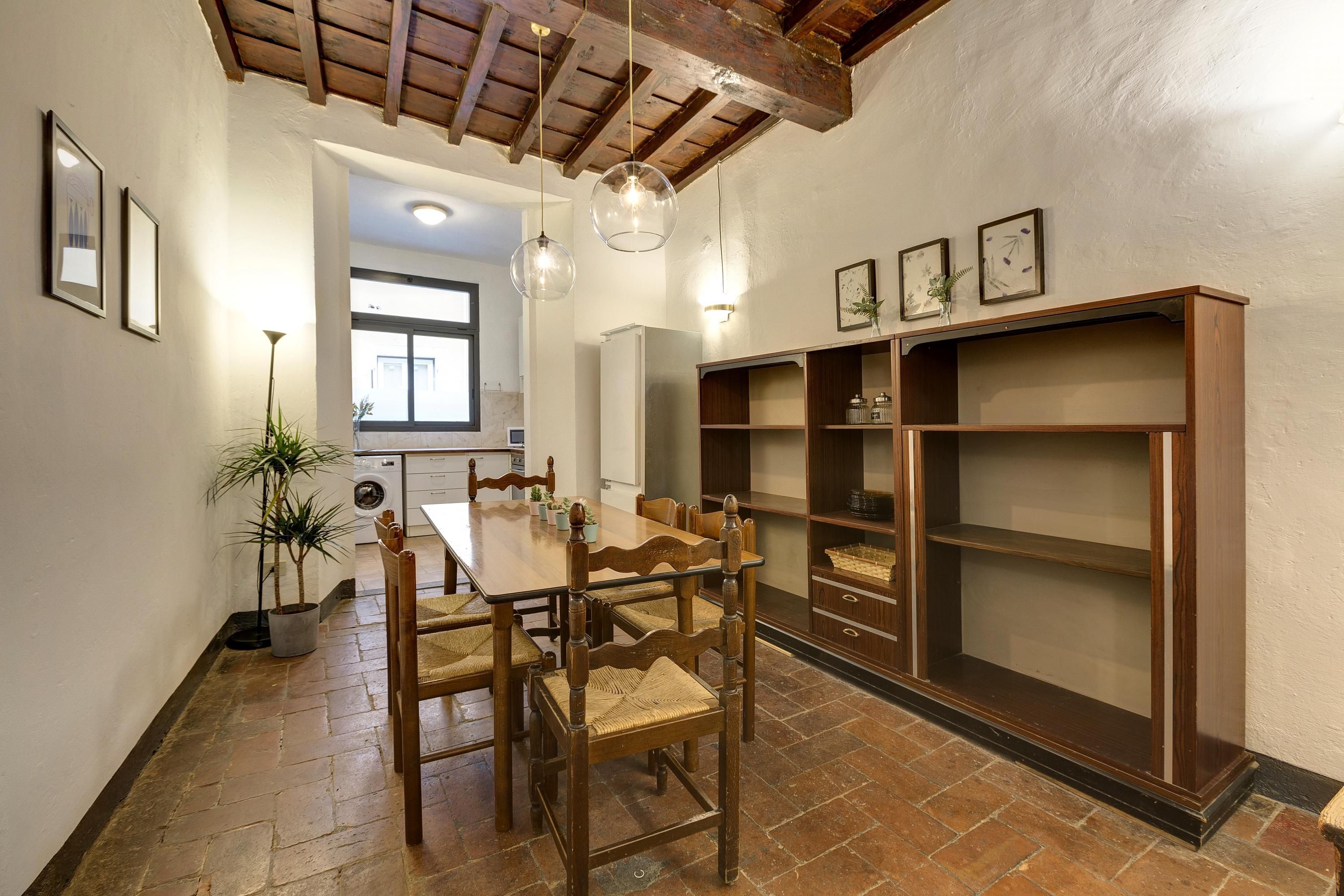 Un coin repas avec une table et des chaises en bois, une bibliothèque intégrée et une plante en pot.