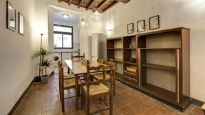 A dining area with a wooden table and chairs, a built-in bookshelf, and a potted plant.
