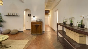 A hallway with a wooden bench, a small table, and potted plants.