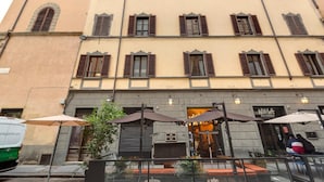 A building with multiple windows and a ground-level cafe with outdoor seating.
