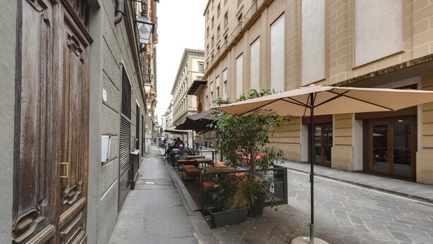 A narrow street with outdoor seating, stone pavement, and traditional architecture.