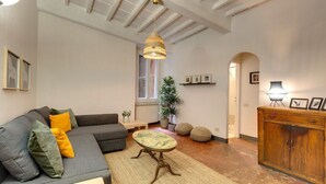 A spacious living room with a grey sofa, a small round table, and a hanging light fixture.
