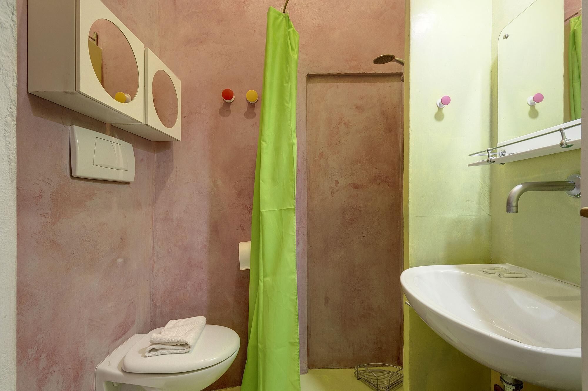 Een badkamer met toilet, wastafel, douchegordijn en spiegel.