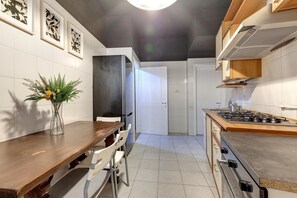 A modern kitchen with a wooden table and chairs, a gas stove, and a refrigerator.