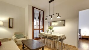 A cozy living room with a wooden coffee table, a sofa, and a dining area with a table and chairs. - Malenchini 6 in Firenze (Florence)